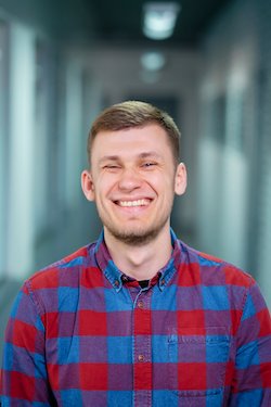 Artur - white European with blue-gray eyes, brown hair and checked flannel shirt is smiling at Instinctools company office